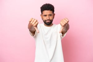 Un hombre negro con un gesto de aprobación para sus seguidores de Facebook sobre un fondo rosa.