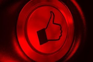 Un botón rojo con un signo de pulgar hacia arriba para promocionar en Facebook.