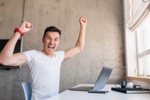 Un hombre está celebrando su exitosa campaña de Facebook en su computadora portátil.