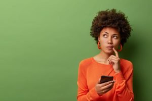 Una mujer joven navegando por su teléfono frente a un fondo verde, como un anuncio de Facebook.