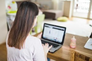 Una mujer sentada en una mesa administrando anuncios de Facebook en su computadora portátil.