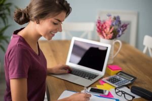 Una mujer optimiza anuncios de Facebook en un escritorio con una computadora portátil y bolígrafos.