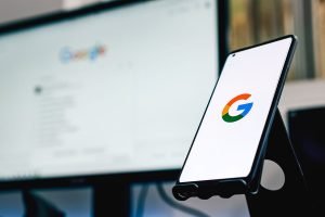 El logotipo de Google se muestra en un teléfono frente a un monitor, mostrando la integración de Google Analytics.