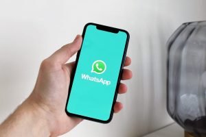 Logotipo de Whatsapp en una mano sosteniendo un teléfono.